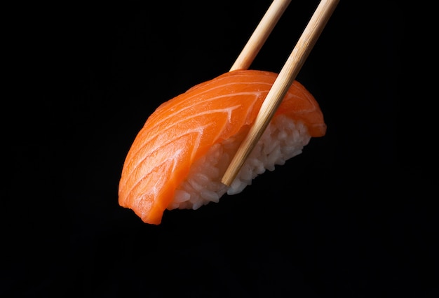 Traditional japanese nigiri sushi with salmon placed between chopsticks