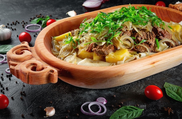 Traditional Kazakh dish Beshbarmak Aromatic roast of lamb and beef with lots of onions and vegetables in a wooden dish Astau