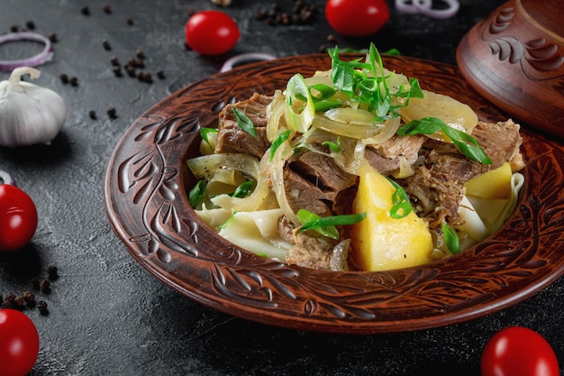 Traditional Kazakh dish beshbarmak with boiled dough onions and mutton and beef in a clay pot