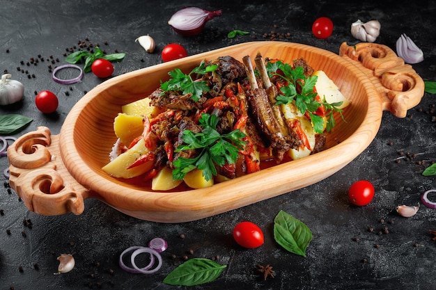 Traditional Kazakh dish Kuirdak Aromatic roast of byproducts lamb meat with lots of onions and vegetables in a wooden dish Astau