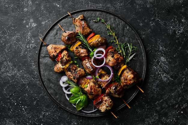 Traditional Kebab Juicy pork skewers with vegetables on a black stone plate Barbecue Top view Free space for text