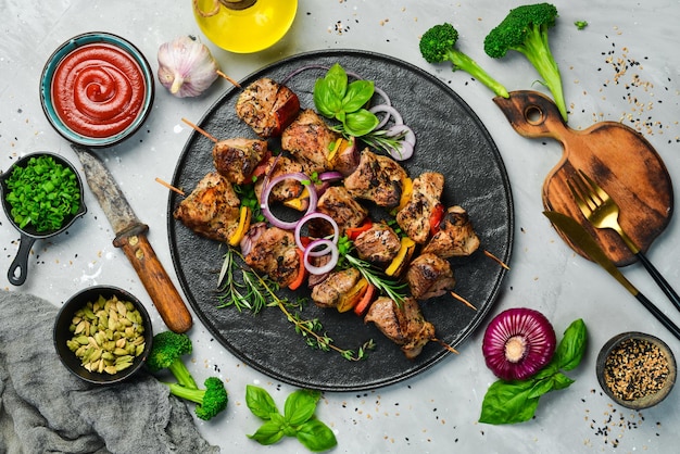 Traditional Kebab Juicy pork skewers with vegetables on a black stone plate Barbecue Top view Free space for text