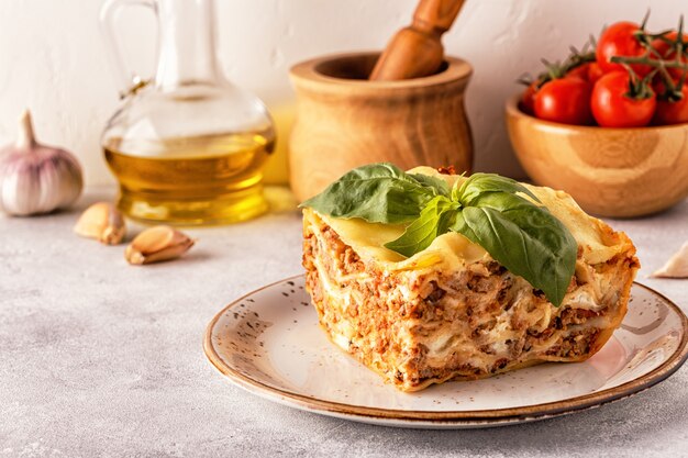 Traditional lasagna made with minced beef bolognese sauce and bechamel sauce topped with basil leaves.