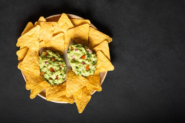 Traditional latinamerican sauce guacamole in cut half avocado mexican nachos chips