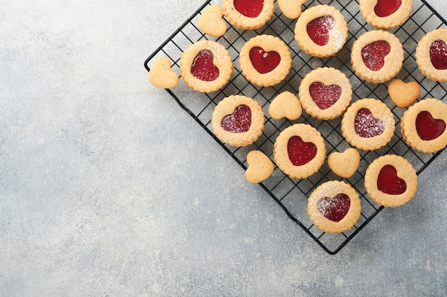 Traditional Linzer cookie with strawberry jam and powder sugar on light grey beautiful background Top view Traditional homemade Austrian sweet dessert food on Valentines Day Holiday snack concept