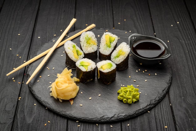 Traditional maki sushi rolls with avocado on a black plate