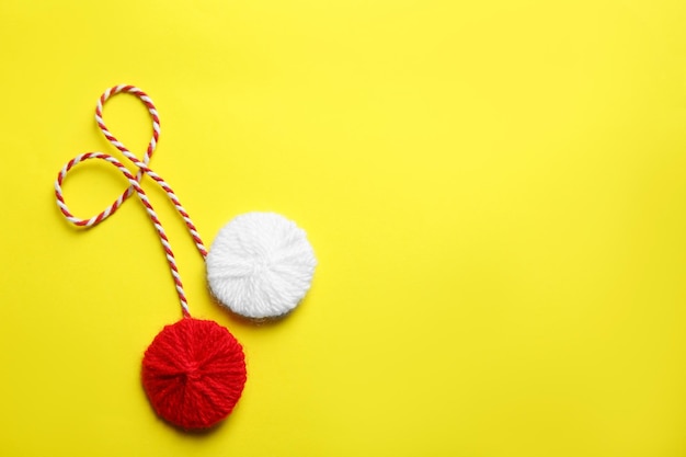 Traditional martisor on yellow background top view with space for text Beginning of spring celebration