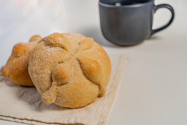 Traditional  mexican bread of the dead and cup of coffee on white table