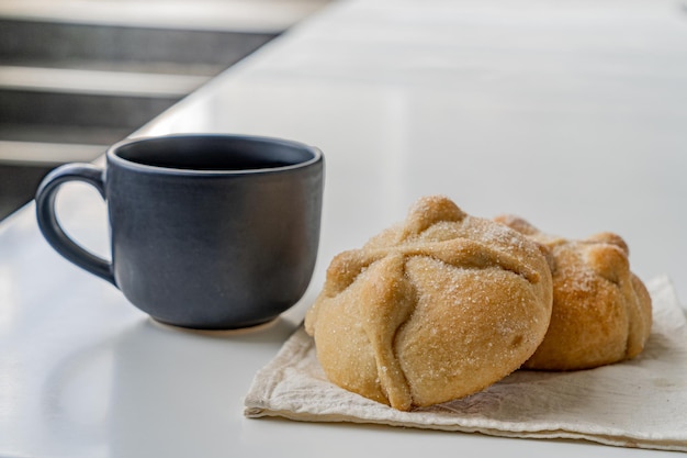 Traditional  mexican bread of the dead and cup of coffee on white table