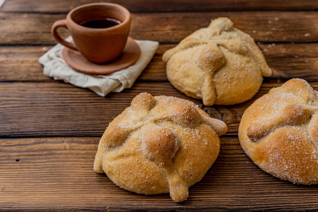 Traditional  mexican bread of the dead and cup of coffee on wood table