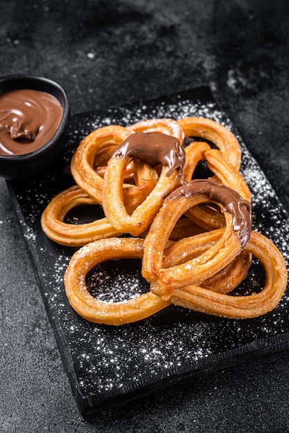 Traditional mexican dessert churros with chocolate sause Black background Top view