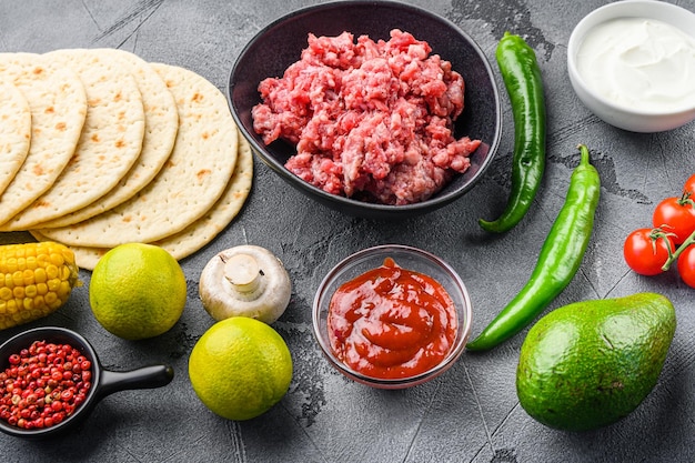 Traditional mexican tortilla ingredients with meat over grey background side view