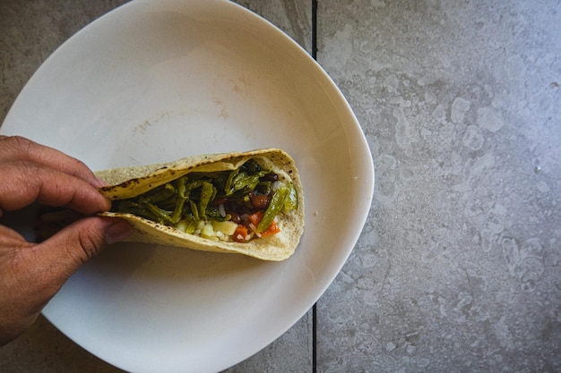 Traditional mexican tortilla with nopales opuntia in hand on the table