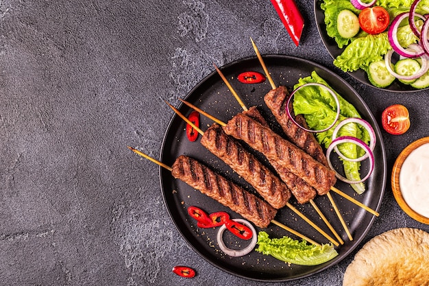 Traditional middle eastern, arabic or mediterranean meat kebab with vegetables and pita bread. Top view.