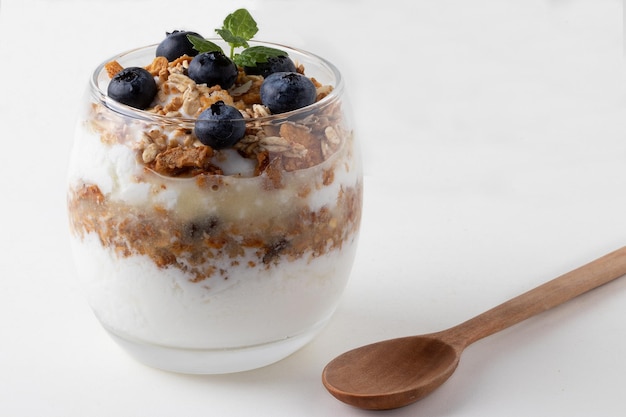 Traditional natural curd with blueberry and granola in a glass cup