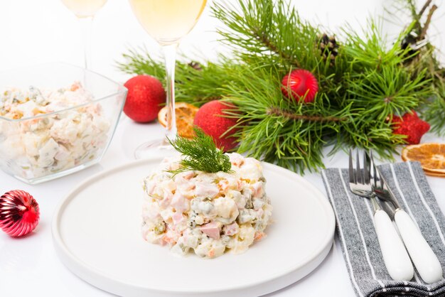 Traditional New Year's salad olivier with festive decorations on a white background, close-up