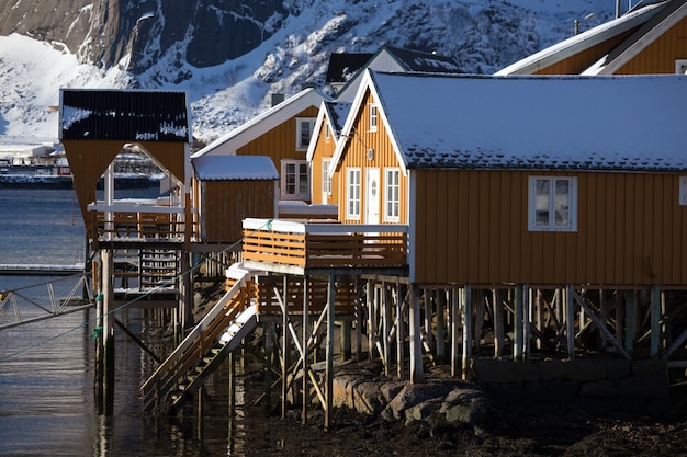 Traditional norwegian wooden house rorbu to stand on the shore of the fjord and mountains in the distance. Lofoten Islands. Norway.