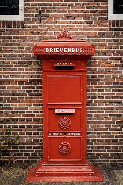 Traditional old Dutch red postbox mounted in a cotswold stone wall