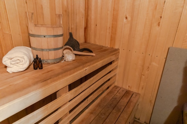 Traditional old Russian bathhouse SPA Concept. Interior details Finnish sauna steam room with traditional sauna accessories set basin towel aroma oil scoop felt. Relax country village bath concept.