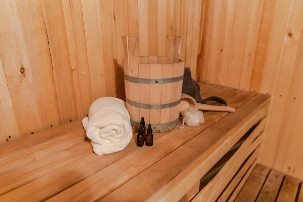 Traditional old Russian bathhouse SPA Concept. Interior details Finnish sauna steam room with traditional sauna accessories set basin towel aroma oil scoop felt. Relax country village bath concept.