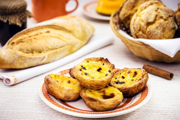 Traditional Portuguese dessert of pastel de nata and bree de lis and bread in the background served with coffee typical Lisbon sweets