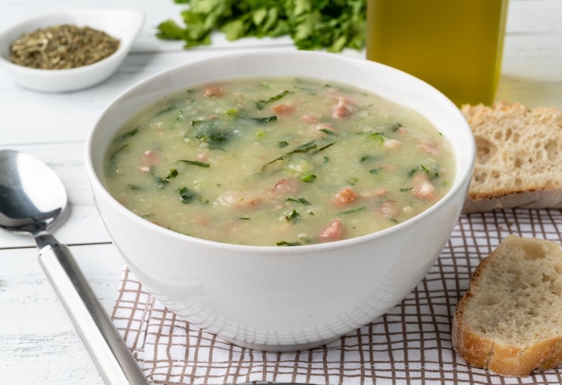 Traditional portuguese green soup with potato green cabbage and sausage in a bowl with bread