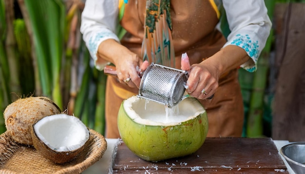 Photo the traditional process of extracting coconut milk with a person grating fresh coconut