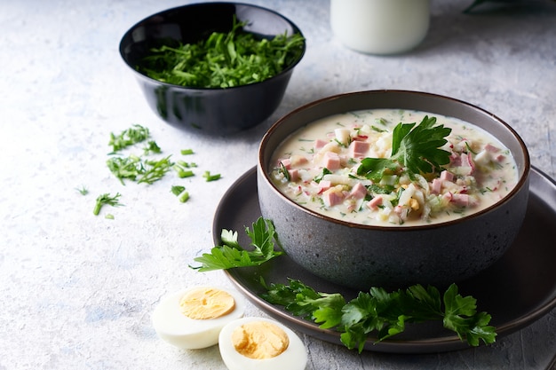 Traditional Russian cold okroshka soup served in a plate with herbs Kefir vegetable soup