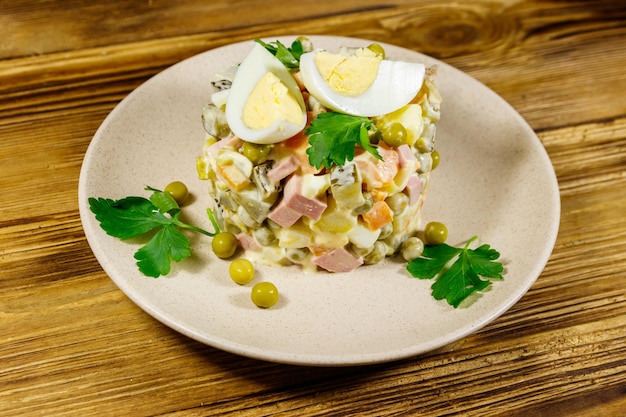 Traditional Russian festive salad Olivier on wooden table