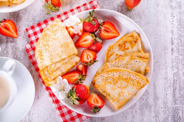 Traditional russian homemade thin pancakes blini crepes with fresh ripe strawberries