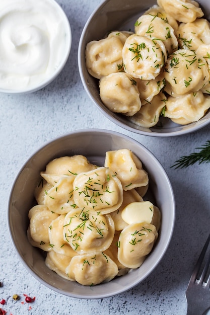 Traditional Russian meat dumplings with sour cream in gray bowl. Russian cuisine concept.