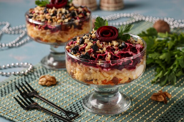 Traditional Russian salad with cheese, beets and carrots, decorated with beet roses, nuts and prunes, portioned serving, Horizontal orientation