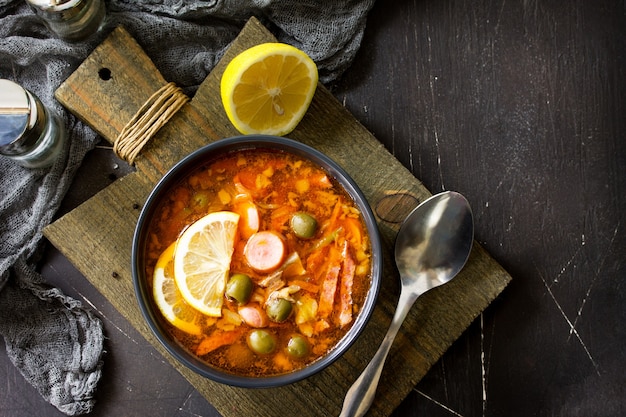 Traditional Russian soup Solyanka with meat sausages vegetables capers pickles and olives