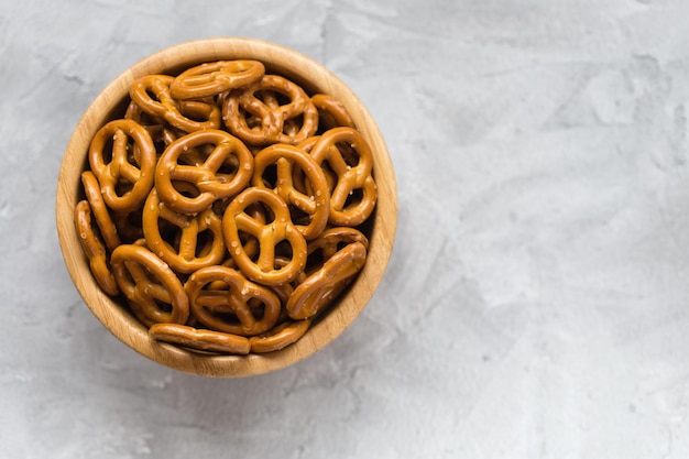 Traditional salty mini pretzels in wooden bowl on a gray background Copy space