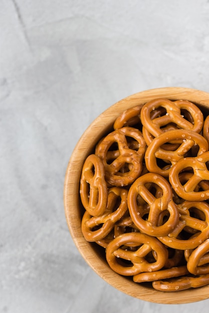 Traditional salty mini pretzels in wooden bowl on a gray backround.