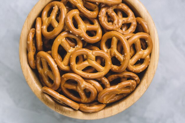 Traditional salty mini pretzels in wooden bowl on a gray .