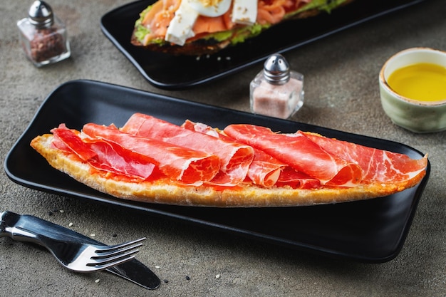 Traditional Spanish breakfast Tostada with different toppings on a dark background