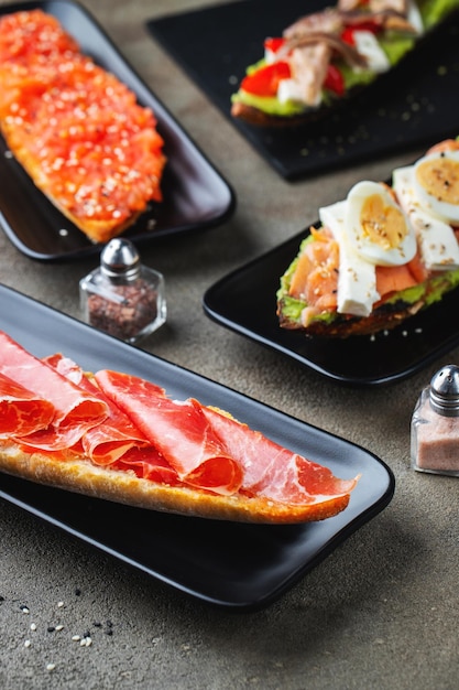 Traditional Spanish breakfast Tostada with different toppings on a dark background