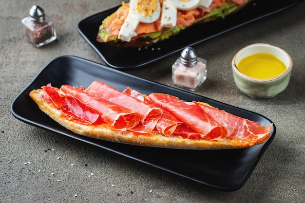 Traditional Spanish breakfast Tostada with different toppings on a dark background