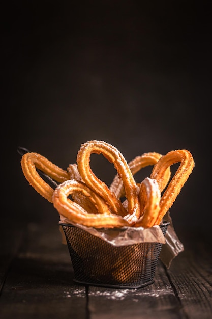 Traditional Spanish churros on the table. Dark and moody photo, rustic style, vertical orientation