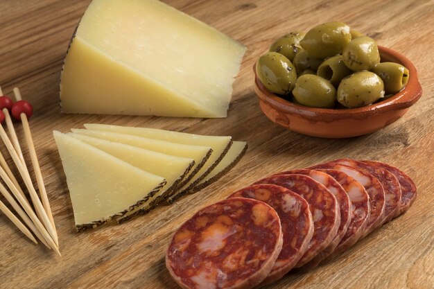 Photo traditional spanish manchego cheese chorizo sausage and olives as tapas on a cutting board close up