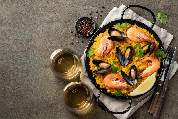 Traditional spanish seafood paella in pan with chickpeas shrimps mussels squid on brown concrete background Top view with copy space