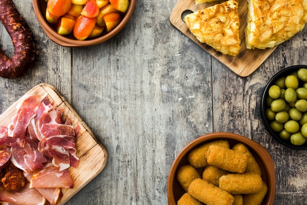 Traditional spanish tapas. Croquettes, olives, omelette, ham and patatas bravas on wooden table copy space