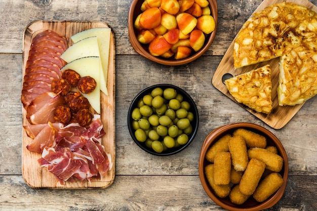 Traditional spanish tapas Croquettes, olives, omelette, ham and patatas bravas on wooden table