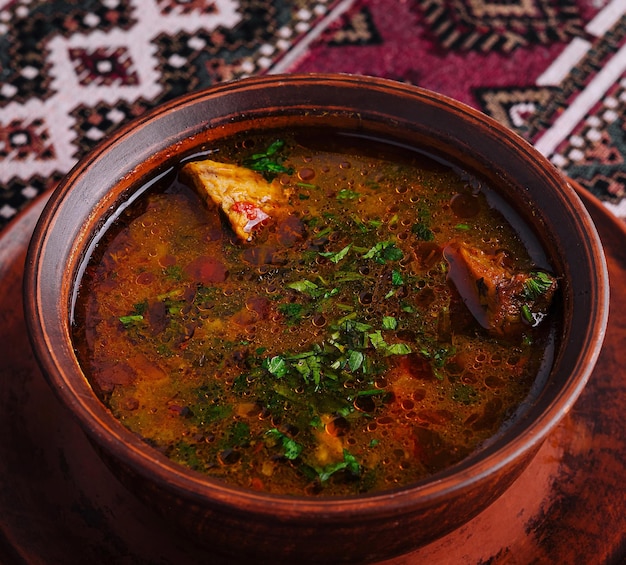 Traditional spicy soup in clay bowl on ethnic textile