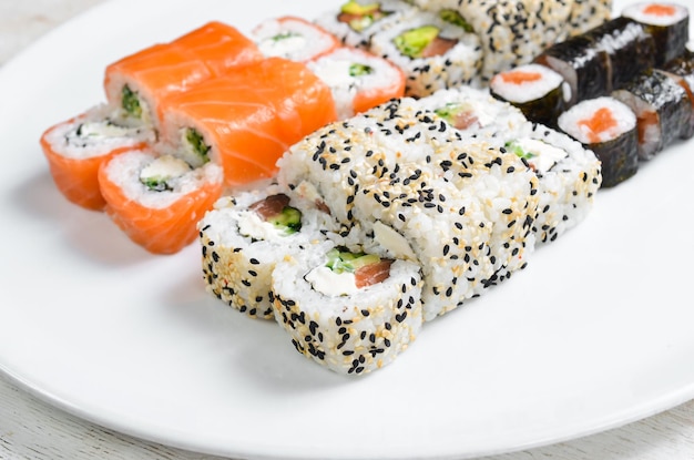 Traditional sushi rolls and maki with sesame avocado and fish Japanese food Top view On a white background