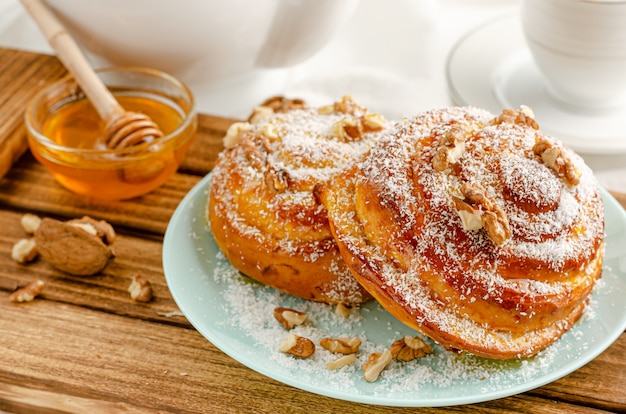 Traditional Swedish bakery or kanelbulle with walnuts on wooden tray. Breakfast or snack concept. Close up