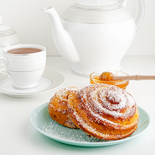 Traditional Swedish fika or cinnamon bun on white breakfast table. Square image