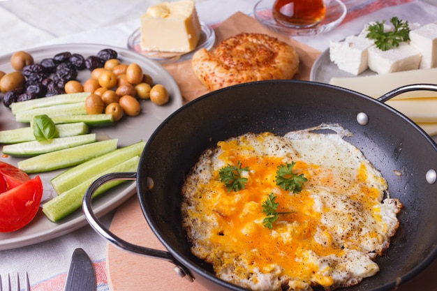 Traditional Turkish breakfast - fried eggs, fresh vegetables, olives, cheese, cake and tea