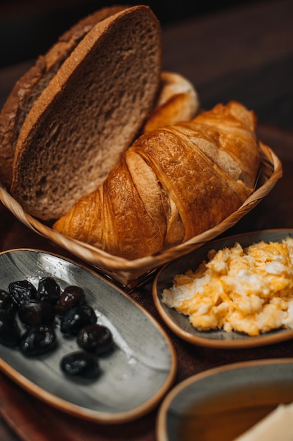 Traditional Turkish breakfast with fried egg, black olives, croissant, bread, cheese, butter in honey and tea on a wooden table. Organic, fresh and tasty food. Vertical